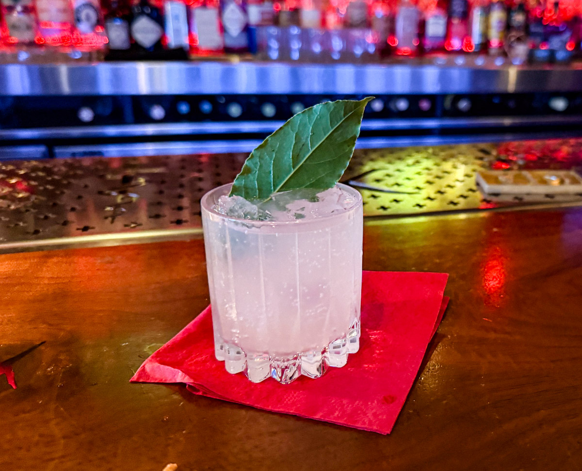 A glass of liquor topped with a leaf.