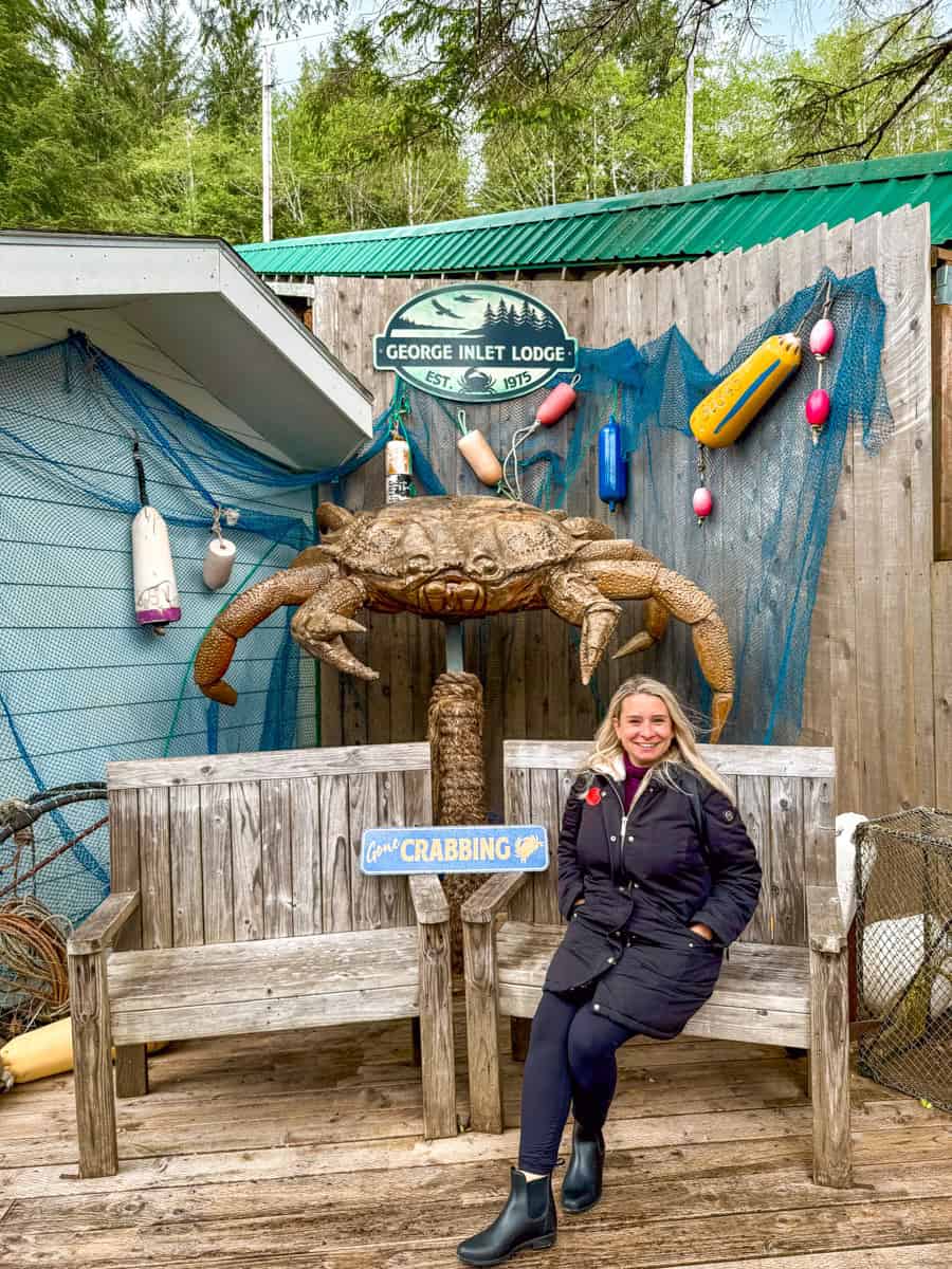 Eleanor is wearing layers while sitting in a chair with a giant crab figure in the back.