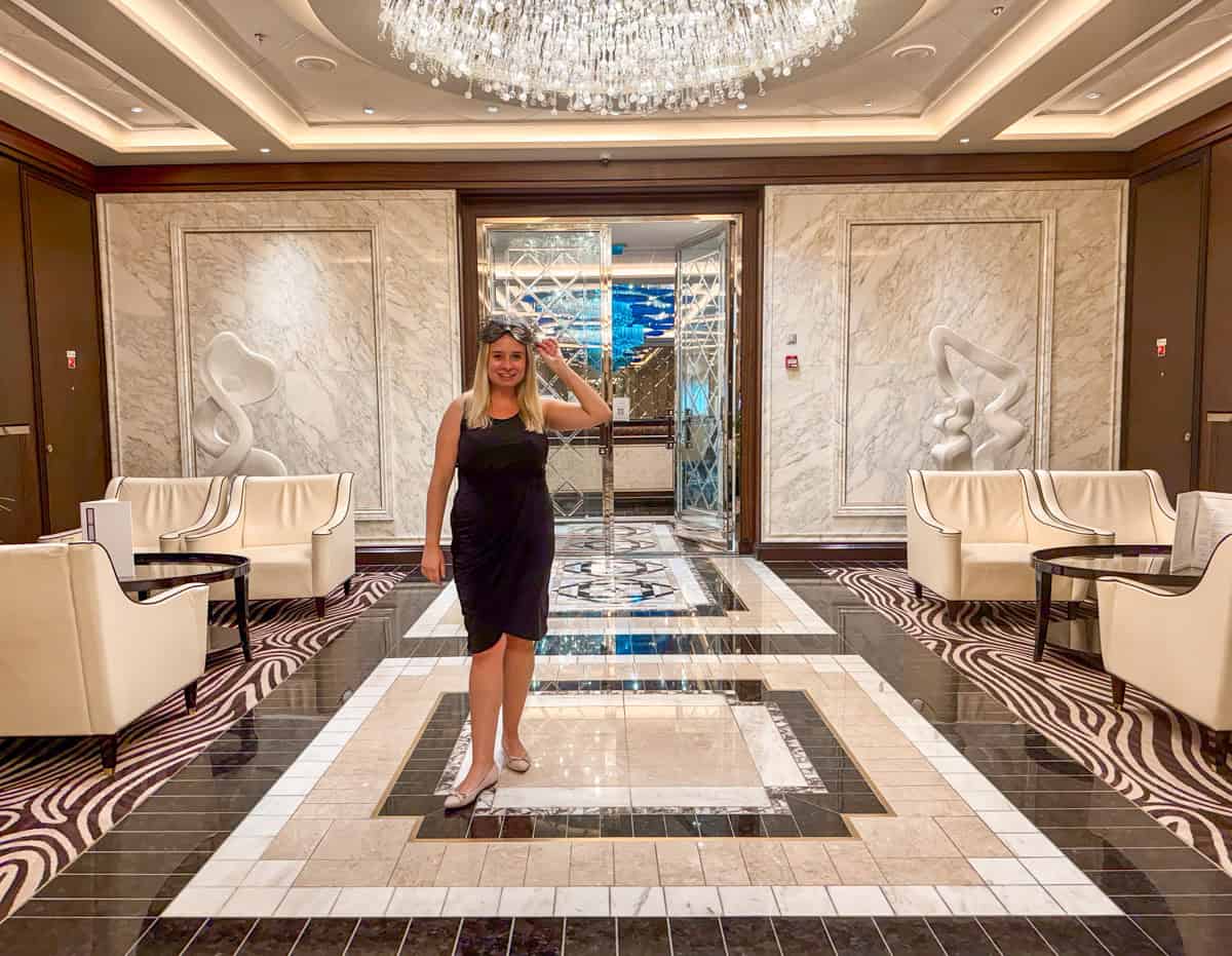 Eleanor is wearing a black dress and closed shoes in a beautiful lobby.